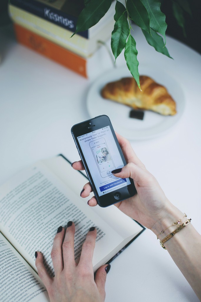 person using phone in front of open book