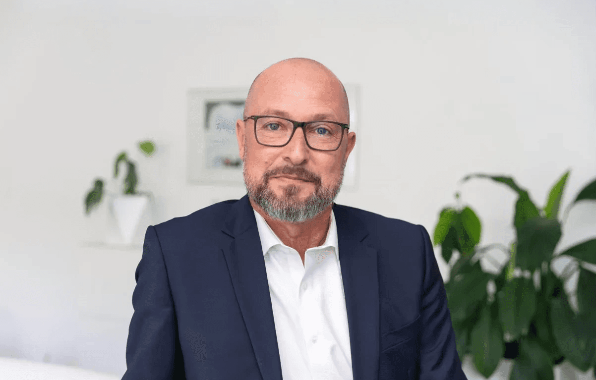 Michael Diehl, Leiter Kooperationen bei der bpa Servicegesellschaft mbH, Portrait eines Mannes mit Brille und grauem Bart im Anzug in einem hellen Büro.