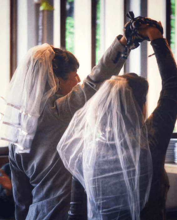 Two people holding hands in wedding attire.