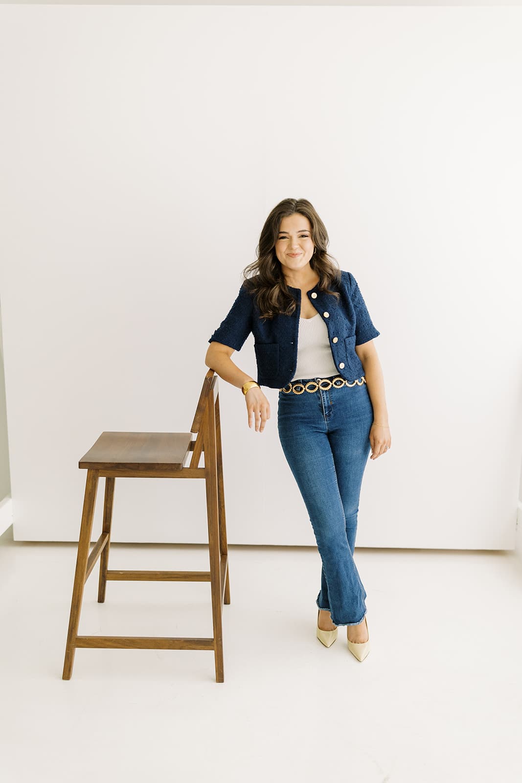 A model poses confidently next to a chair in the bright, natural light setting of Revelator Studio in Shreveport, captured by photographer Andy Roberts, showcasing the studio’s versatile space for creative projects.