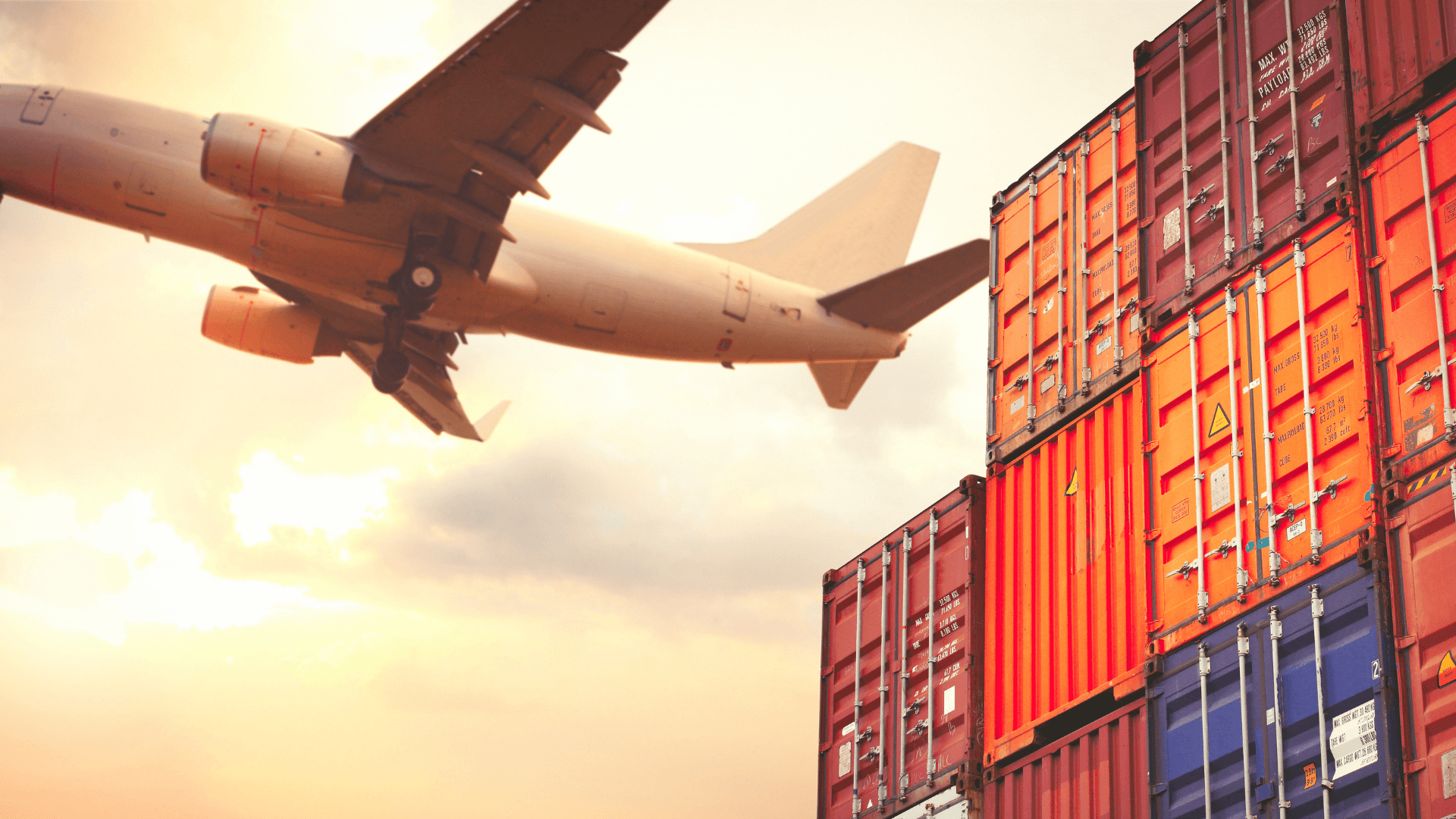 Cargo airplane taking off above a stack of colorful shipping containers.