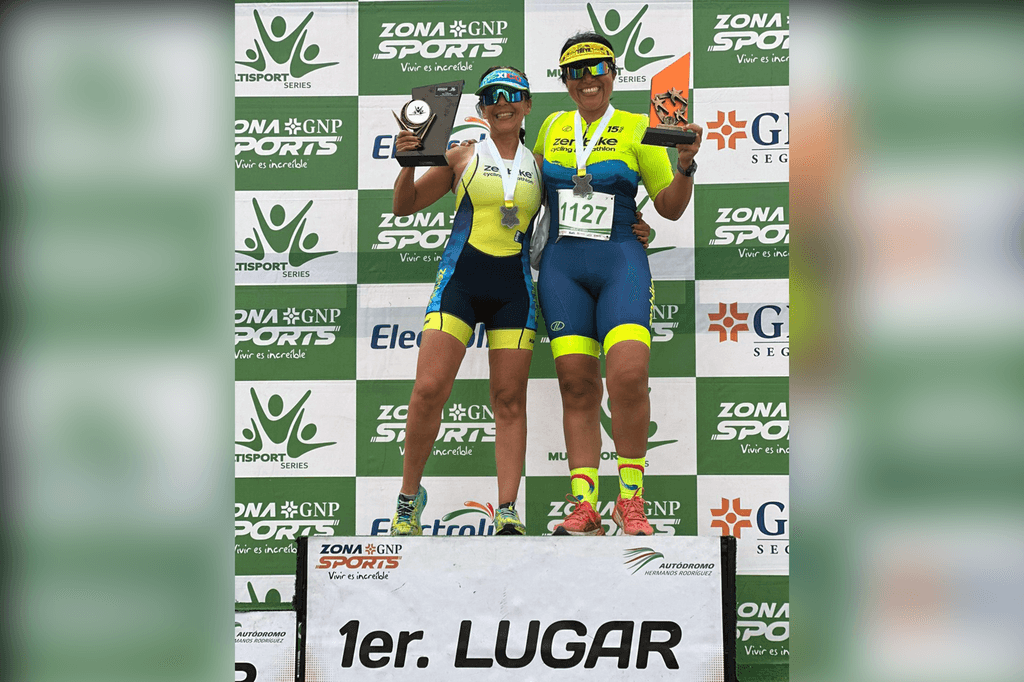 Dos duatletas en el podio levantando trofeos de primer lugar.