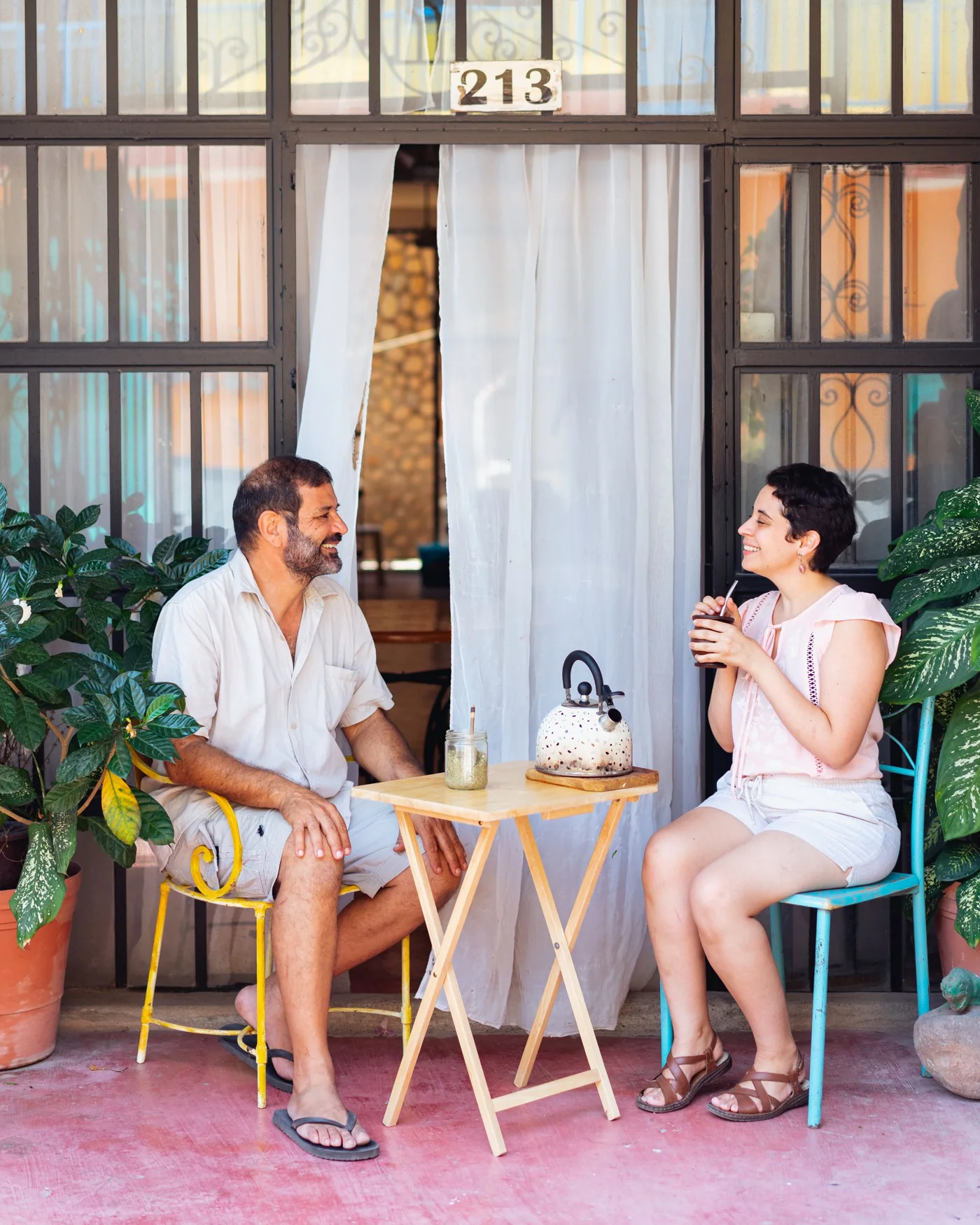 A man and a woman talking over tea outside their front door