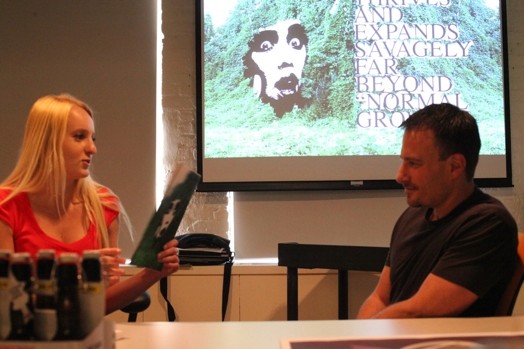A photo of a woman showing an image to a man while sitting at a desk.