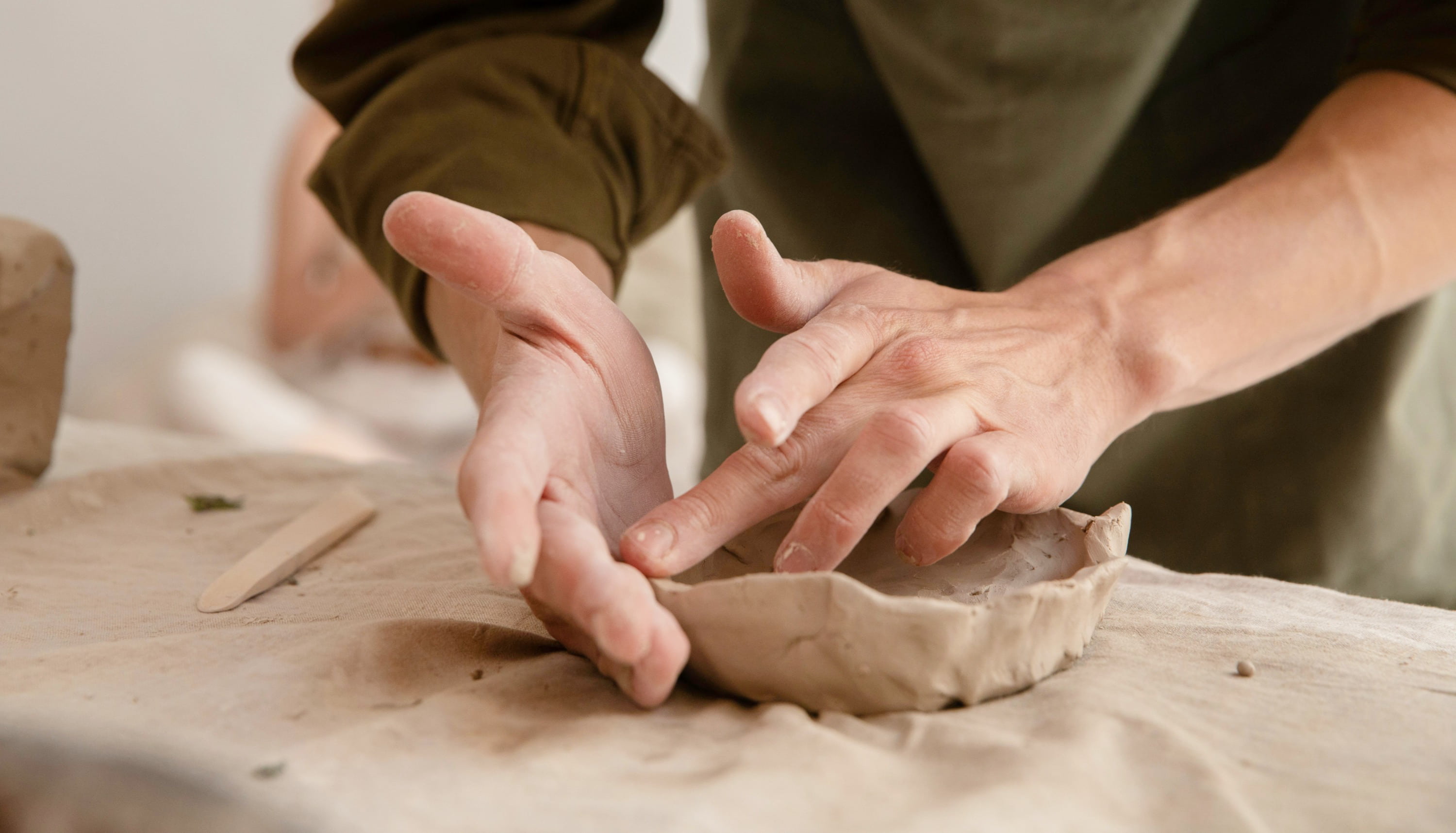 Cours de modelage céramique à Guérande : mains façonnant une pièce en argile sur toile, initiation poterie