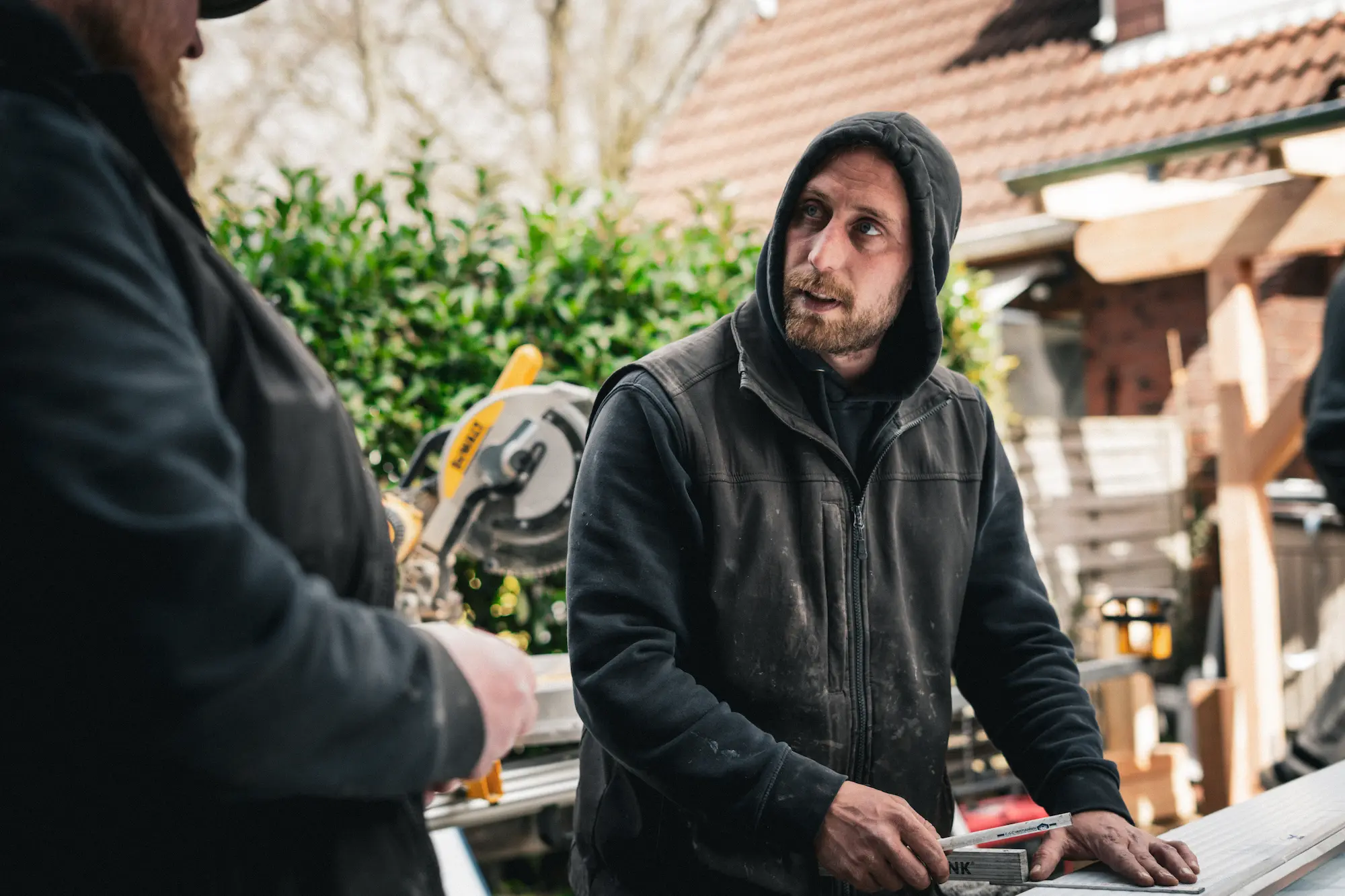 Ein Zimmermann der eine Kapuze trägt und nach Links schaut