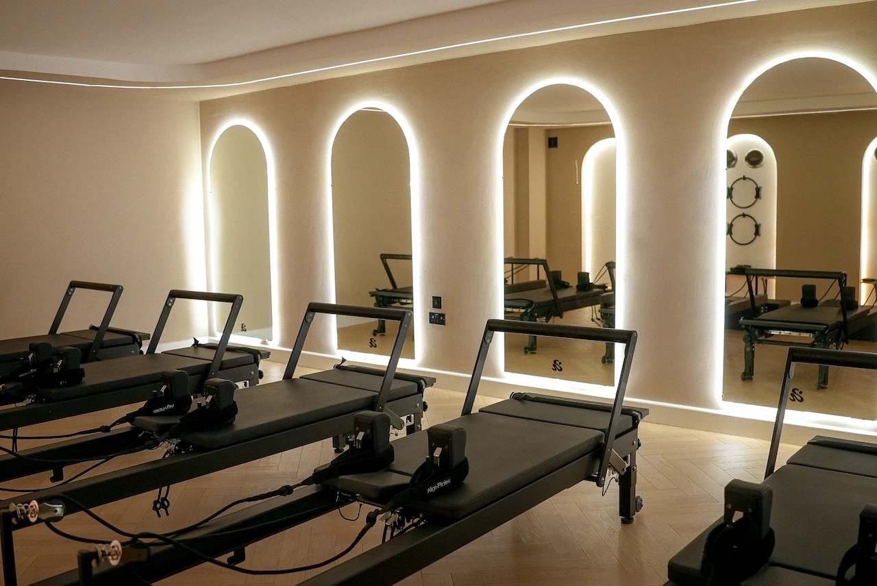 Modern reformer Pilates machines lined up in Sculpt studio with warm ambient lighting