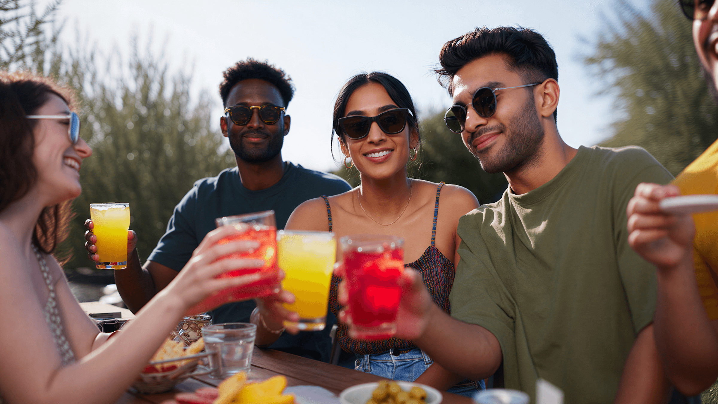 Friends toasting drinks outdoors on a sunny day