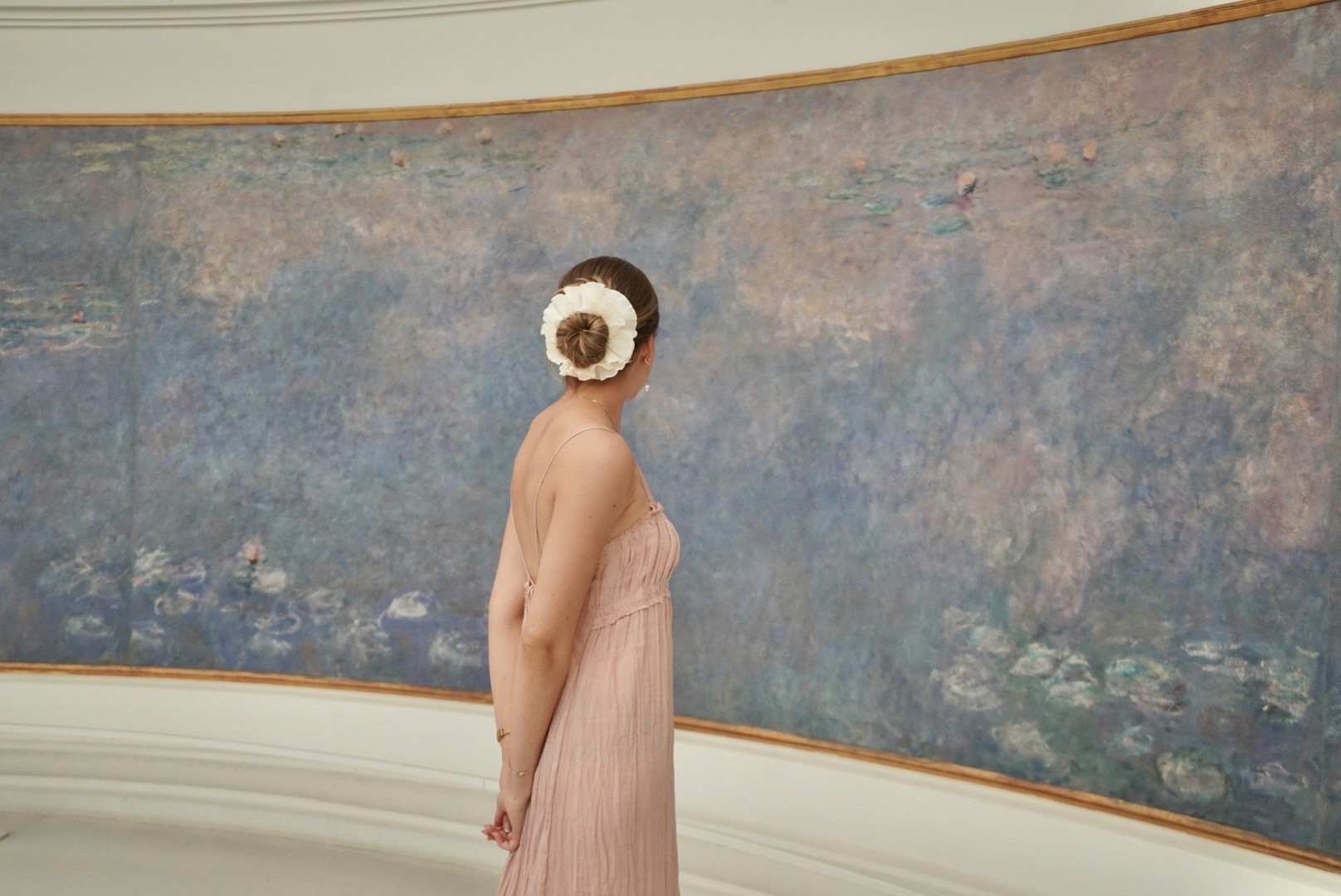 A model dressed in a mustard yellow blazer and cream trousers poses confidently against a minimalist background with sky blue and beige tones, exuding a modern and chic fashion aesthetic.