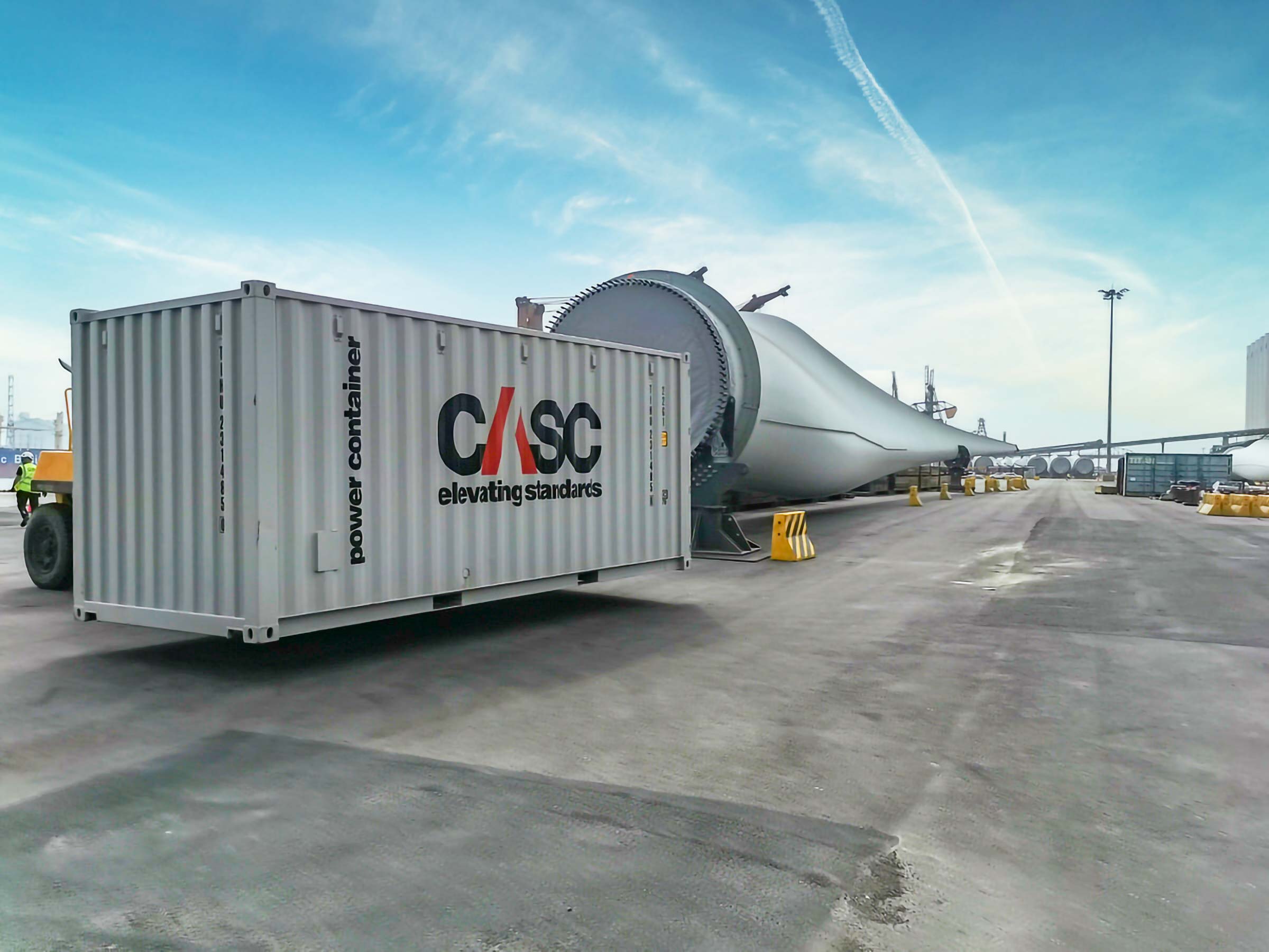 CASC power container positioned beside wind turbine components at an offshore wind port.