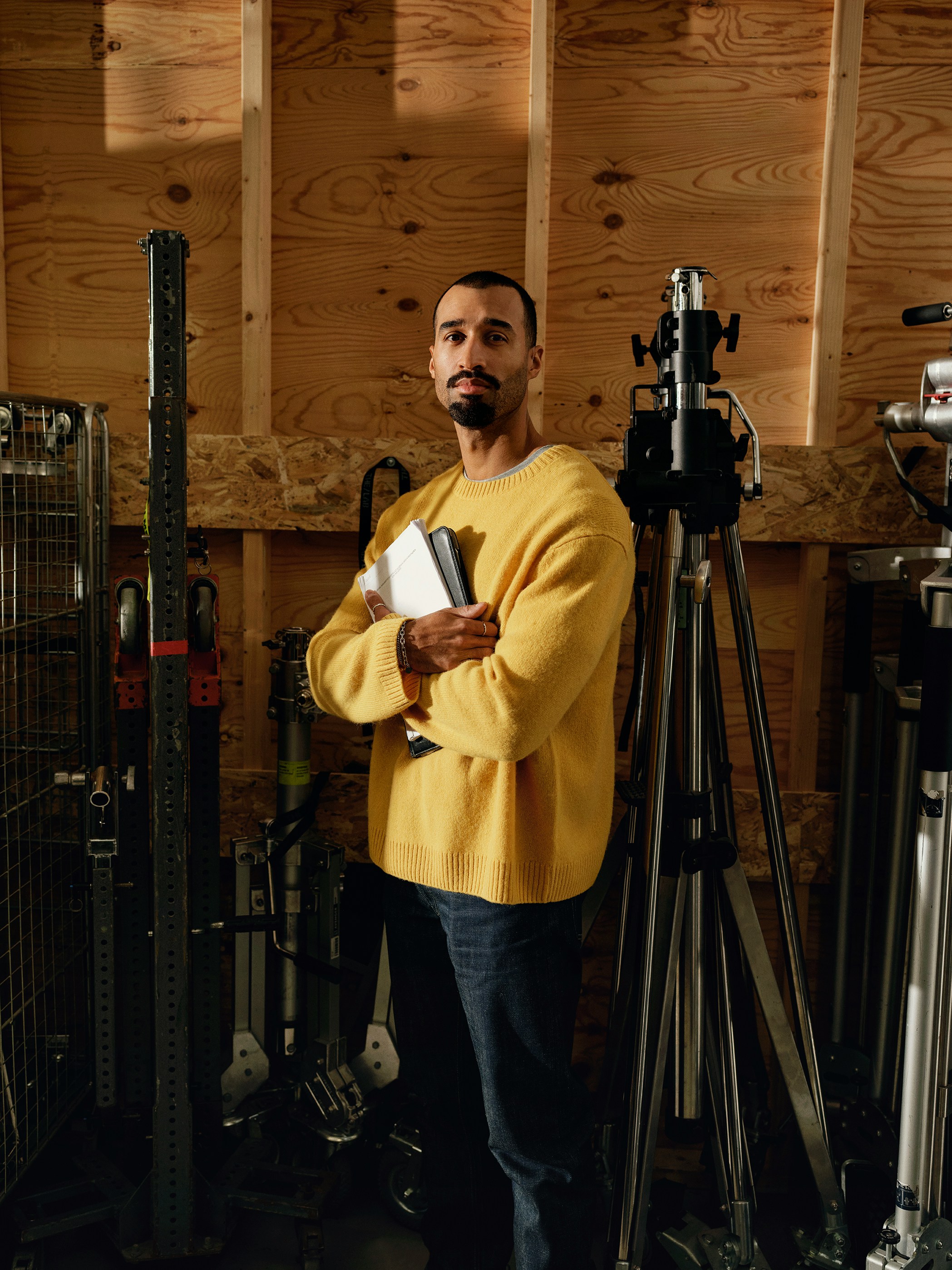 Man holding books with arms crossed in studio.