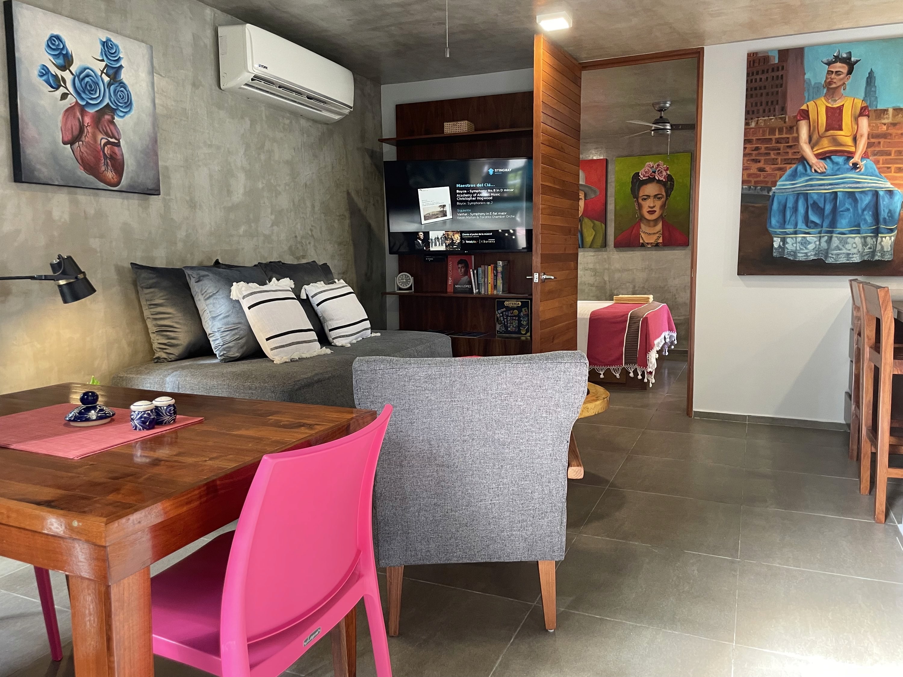 Sala y comedor de Casa Frida con muebles de madera y obras de arte