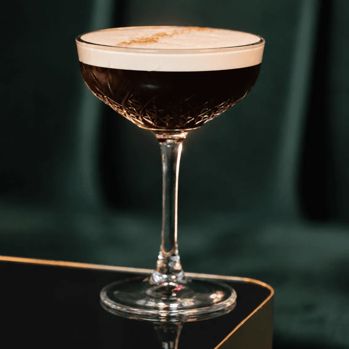 Dark cocktail with white foam in stemmed glass