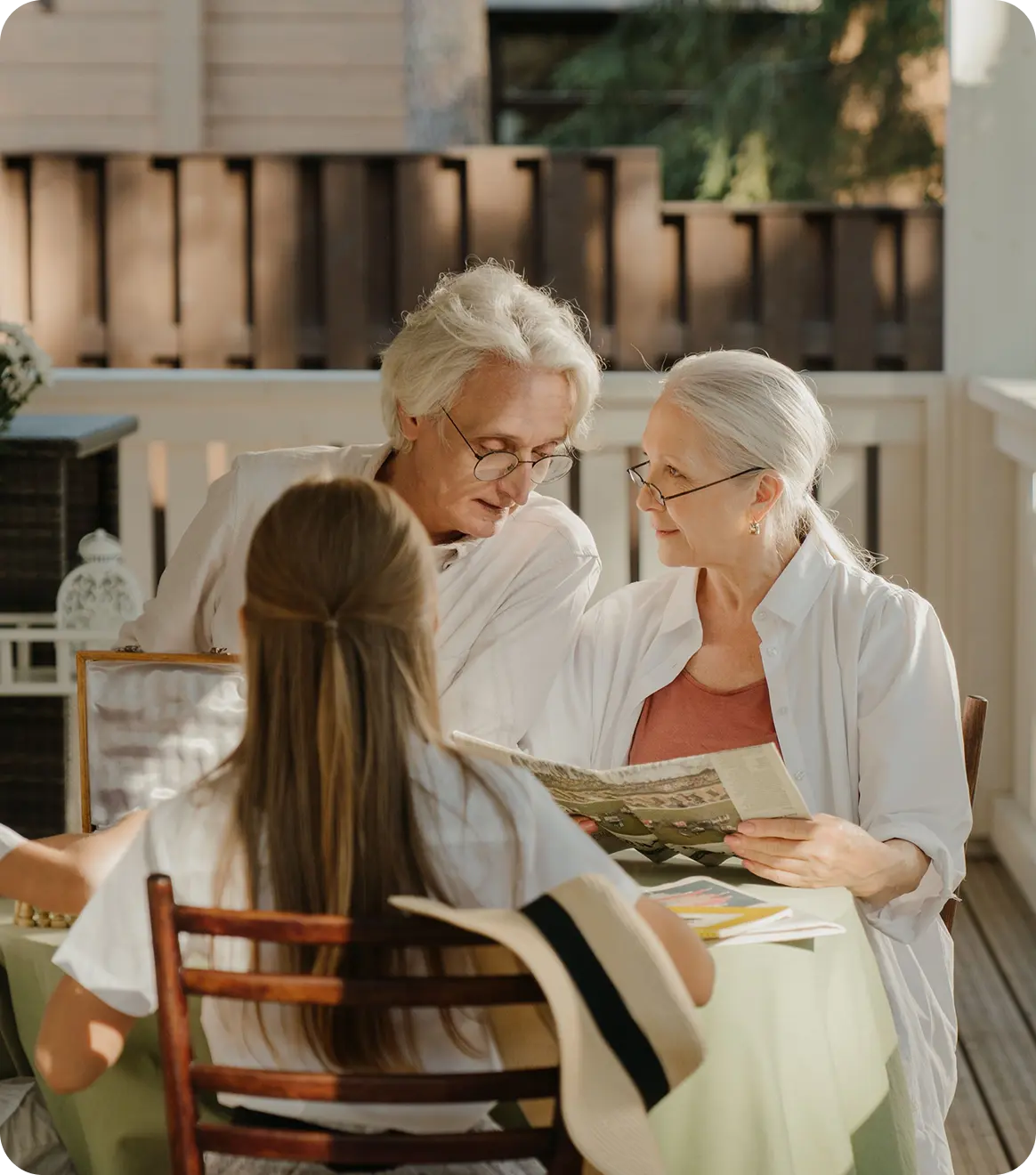 Elderly residents sharing a meal and conversation in a warm, home-like care environment.