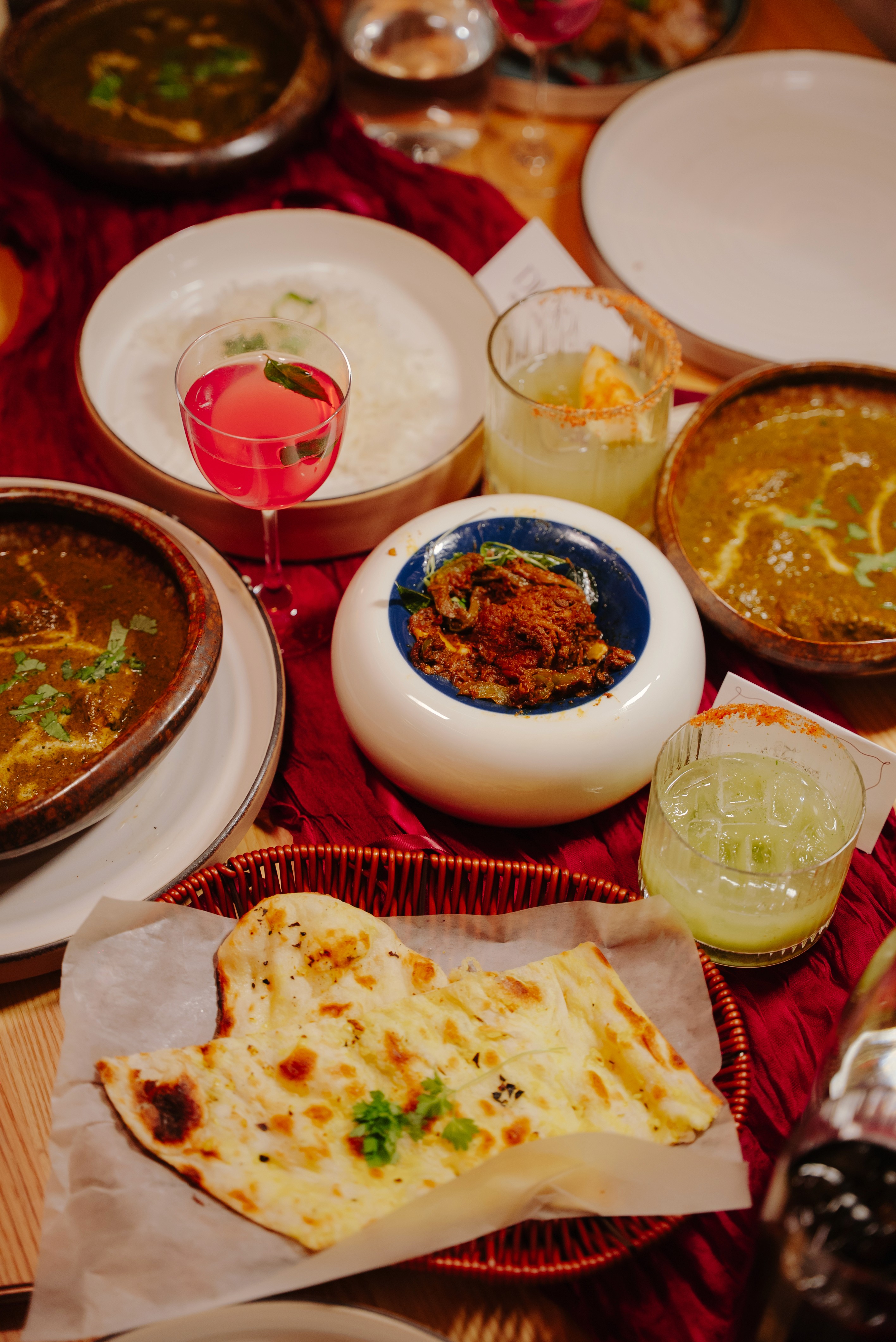 Curated Indian tasting menu at Dhoom featuring naan, signature curries, cocktails, and small plates served during an exclusive pre-launch dinner.