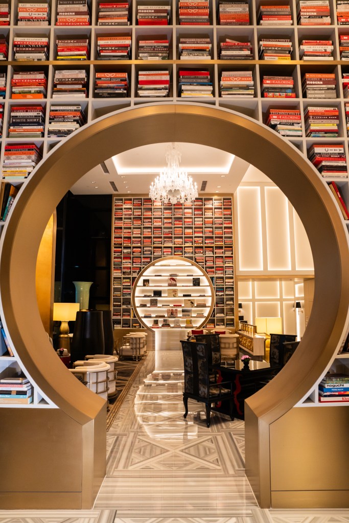 Interior view of a stylish library or reading area featuring a circular archway adorned with bookshelves, a chandelier, and elegant furniture.