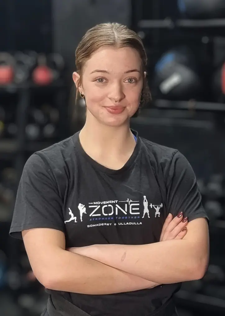 Coach Anto Newton posing in The Movement Zone shirt inside the training facility.