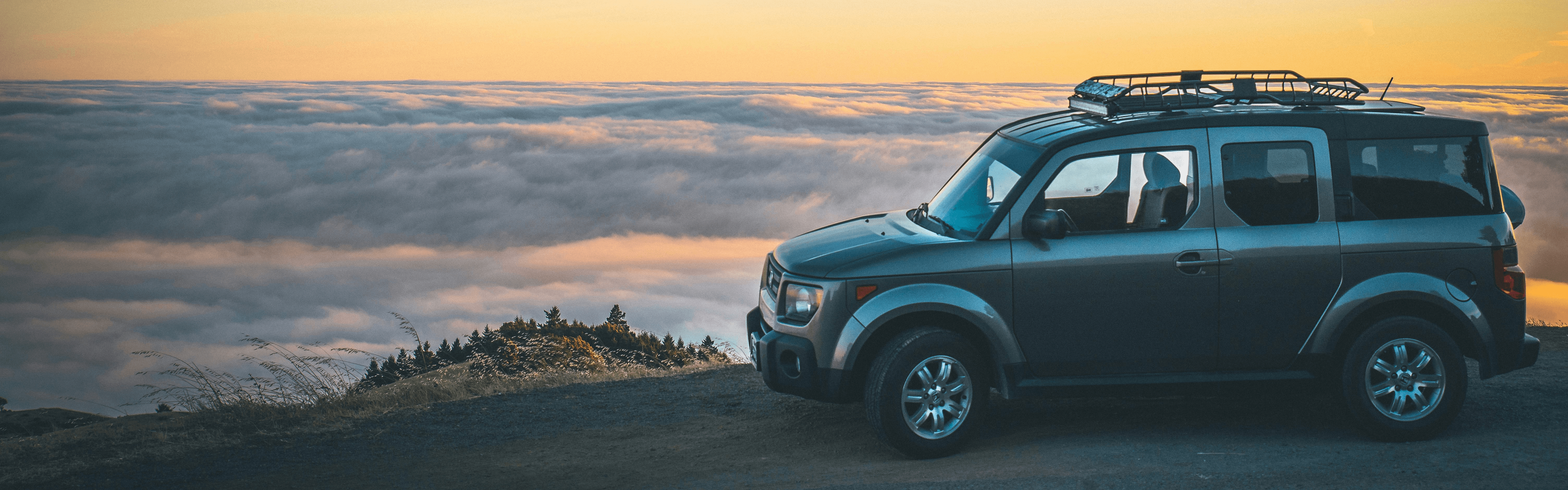 grey SUV beside sea of cloud