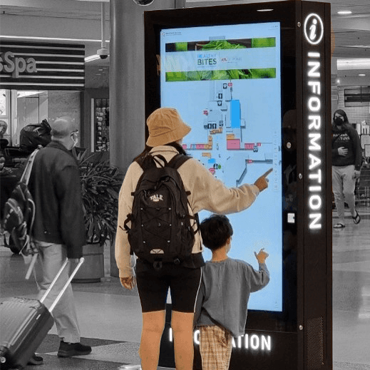 A parent and child using a kiosk in an airport