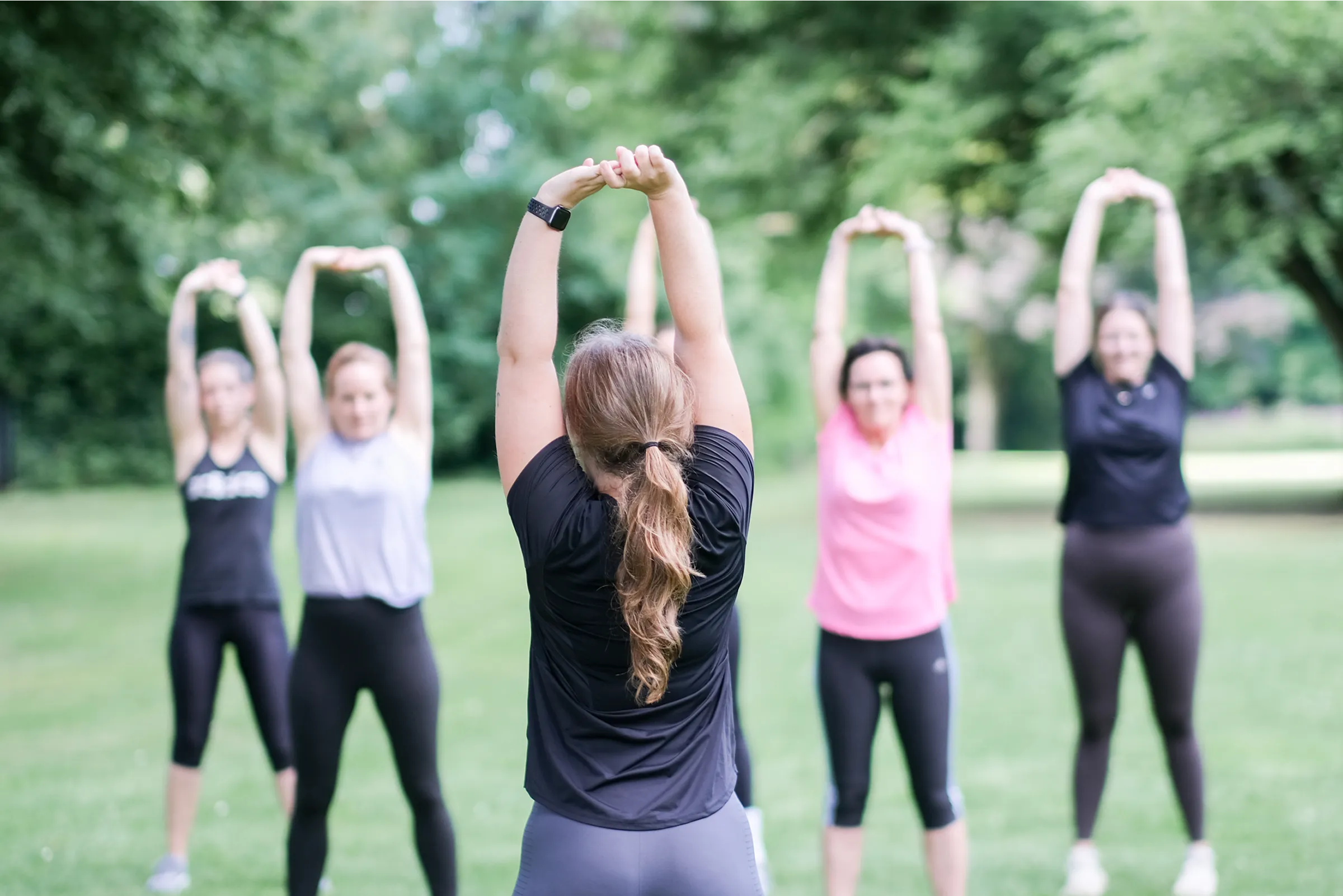 Gruppe von Menschen streckt die Arme in die Luft, um sich zu stretchen