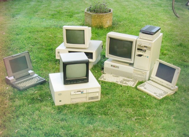 Several outdated desktop computers, monitors, and laptops sitting abandoned on grass, representing old hardware in need of computer repair in Fort Myers.