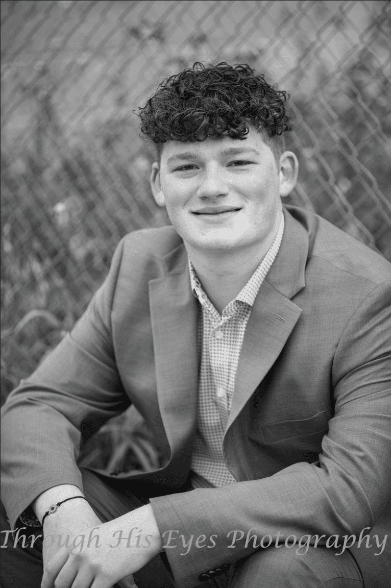 A thoughtful young person with dark hair gazes to the side, captured in soft black and white lighting.