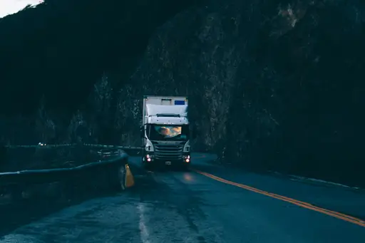 camión con remolque pasando por la carretera cerca de la barandilla de seguridad