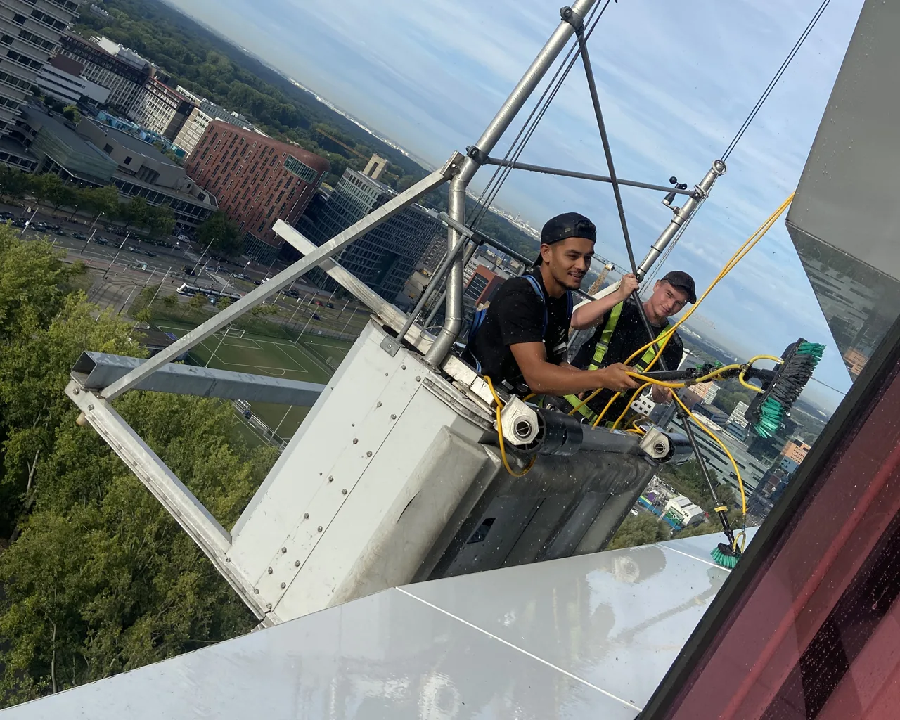 Twee glazenwassers van Qlean Facility Group aan het werk in een gevelinstallatie op hoogte