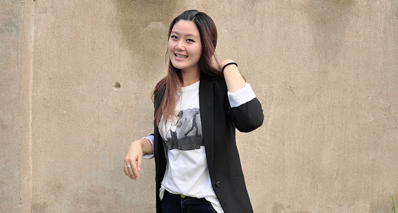 A photo of a woman witting in front of a wall.