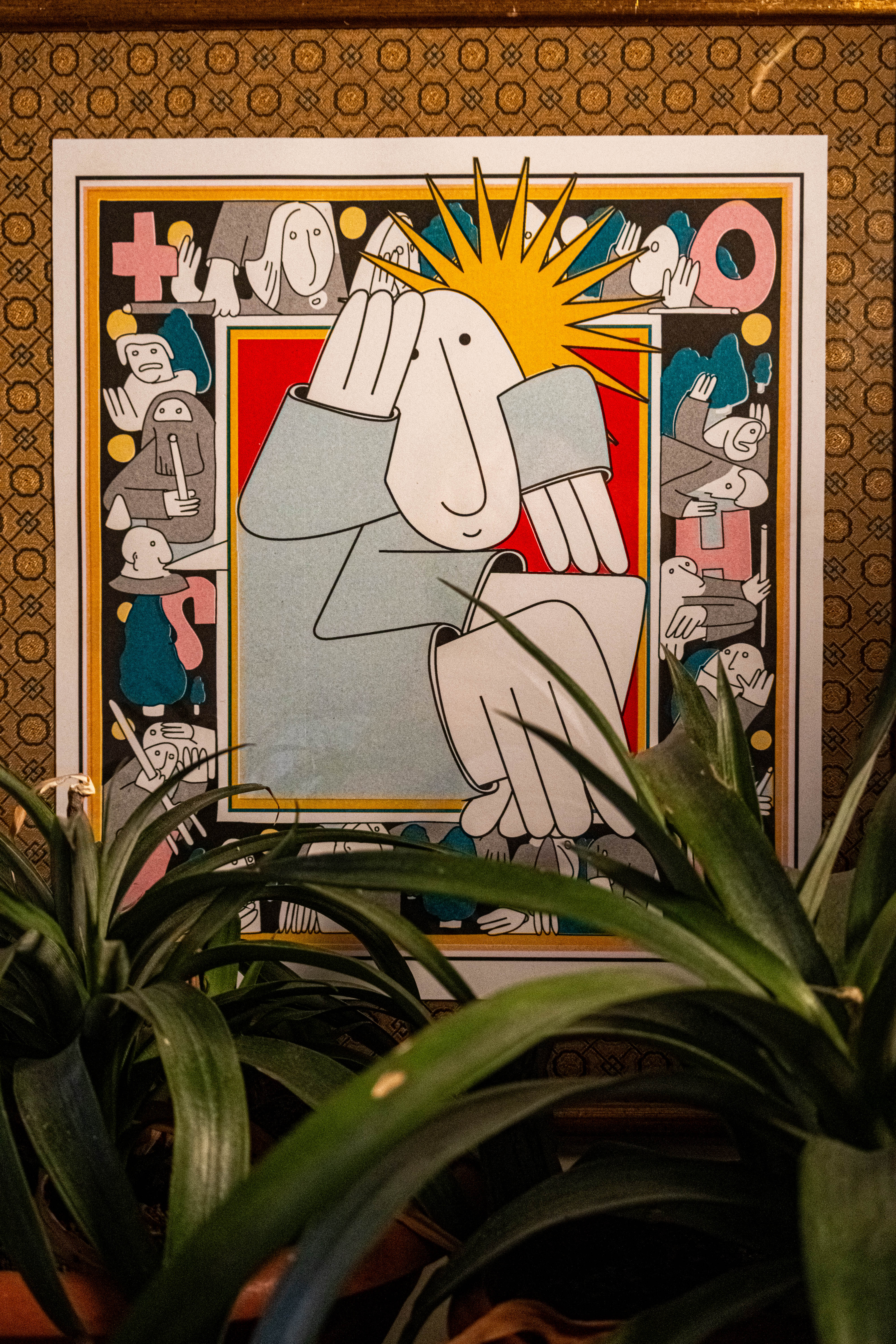 A colorful framed print featuring happy cartoon figures with plants in the foreground. The background has bright patterns.
