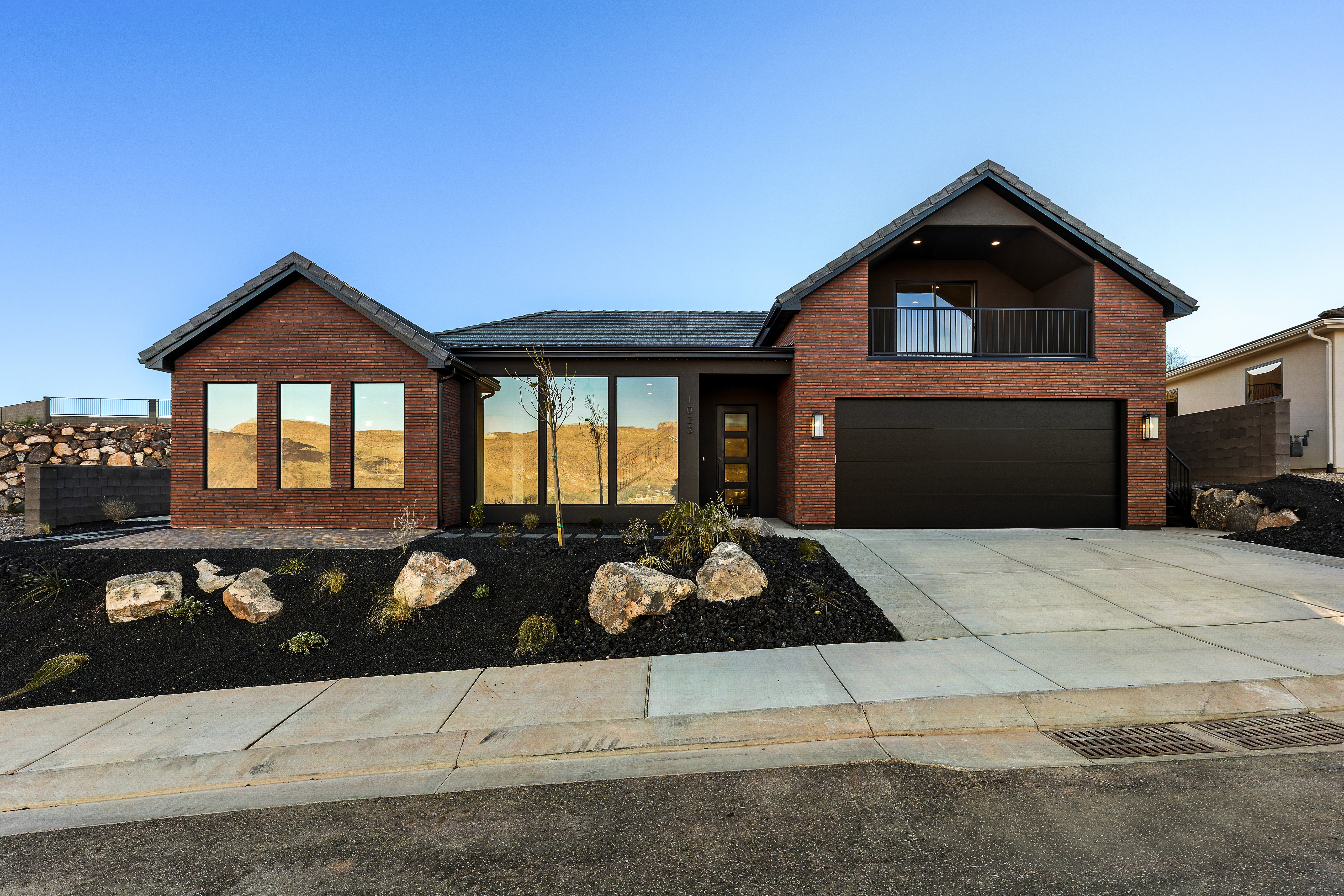 Front exterior of a custom Hurricane, Utah home with modern thin red brick and black metal finishes.