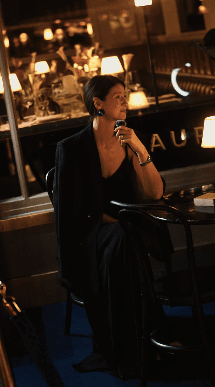 Bride sitting on ground against wall, groom standing nearby