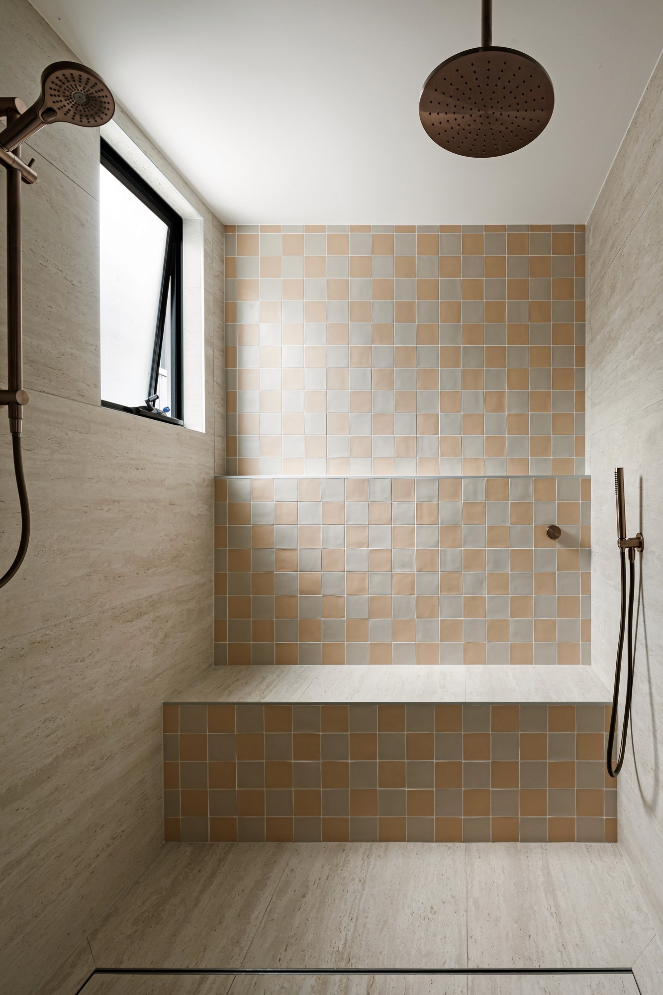 Ensuite shower with warm peach-toned tiles and a built-in shower bench.