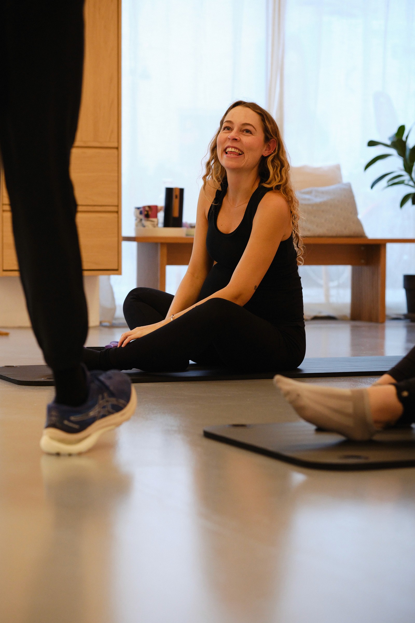 Pregnant woman sitting on a pilates mat and smiling