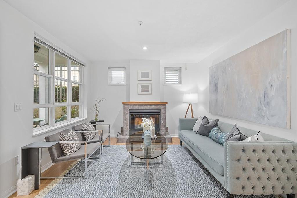 Bright, modern living room with a white color palette, a cozy fireplace, and stylish furniture.