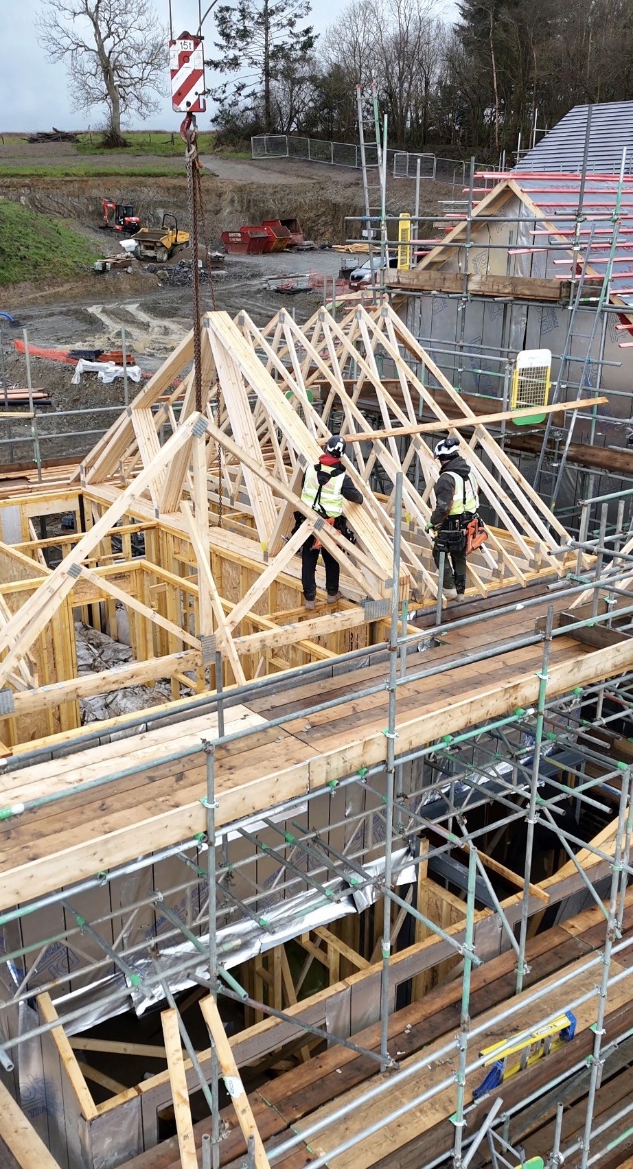 A serene outdoor seating area with two chairs, surrounded by lush greenery and a glassed-in structure.
