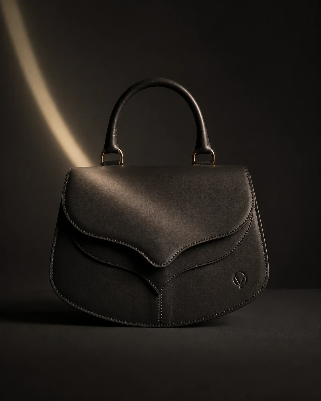 Black leather handbag seen from the front in directional light.