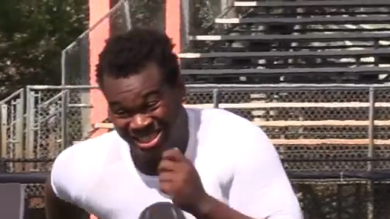 Close-up of Evan Neal in a white practice shirt, smiling, face centered
