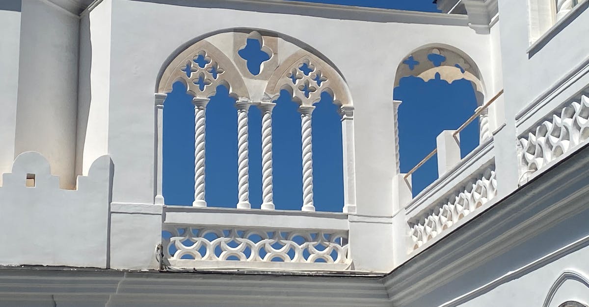 Close-up of intricate white arches with Gothic designs against a clear blue sky.