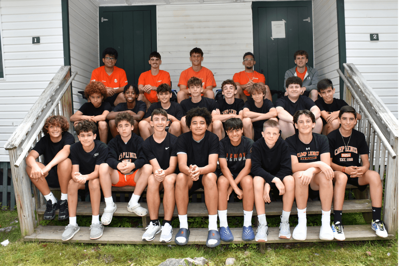 Group of campers sitting on the steps outside a cabin