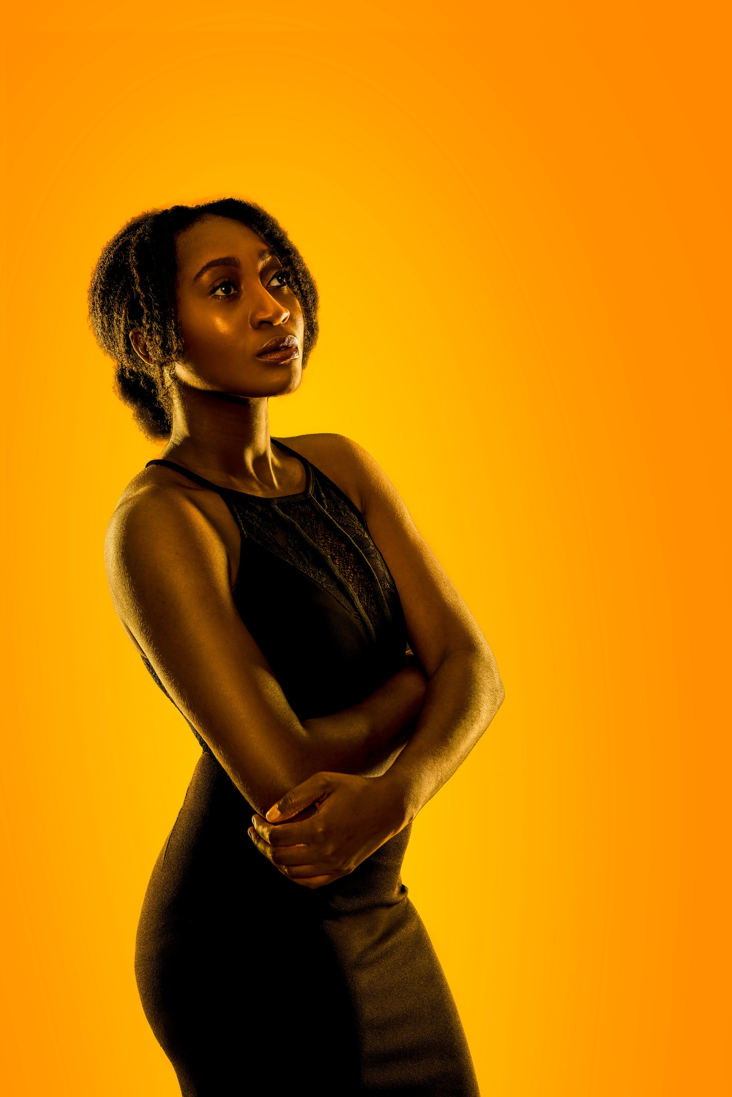 Fashion portrait featuring a model illuminated by warm golden studio lighting and rich contrast.