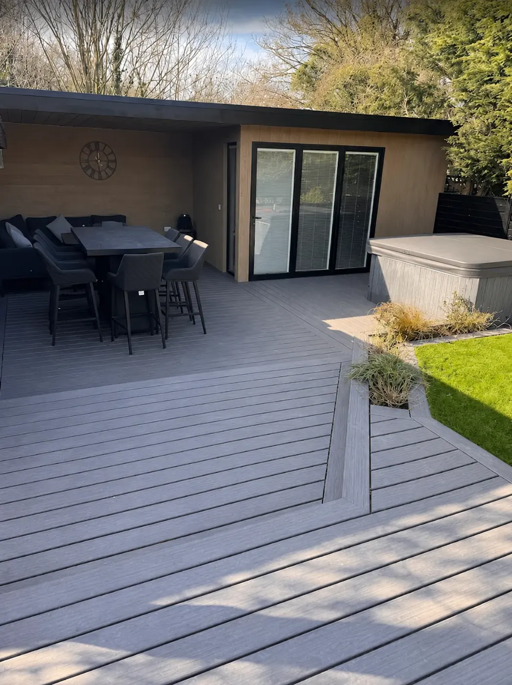 Two-tone grey Trex deck with outdoor dining and hot tub