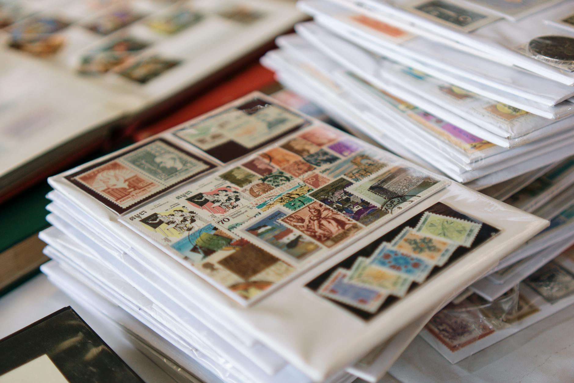 Stacked collector albums filled with colourful postage stamps from various countries on a white surface
