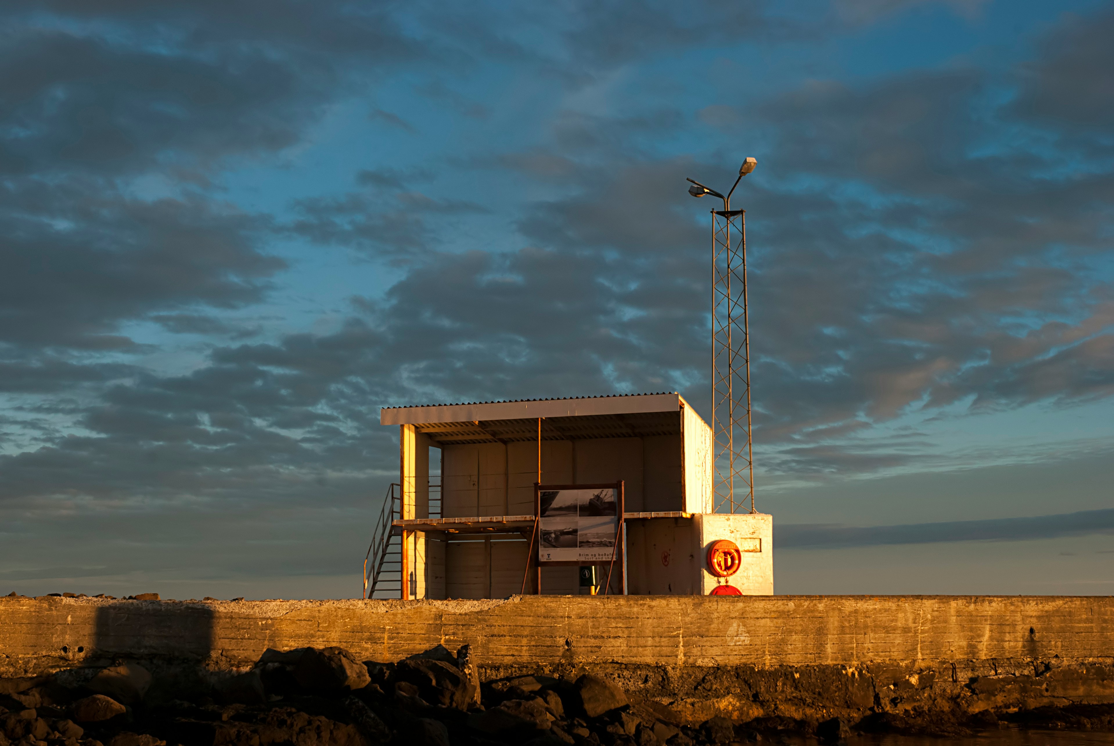 Small shelter with an information board along the seawall of Stokkseyri, Iceland.