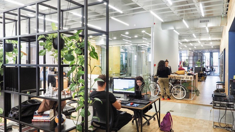 Modern office interior with glass walls, wooden accents, and a person walking up a staircase in motion blur.
