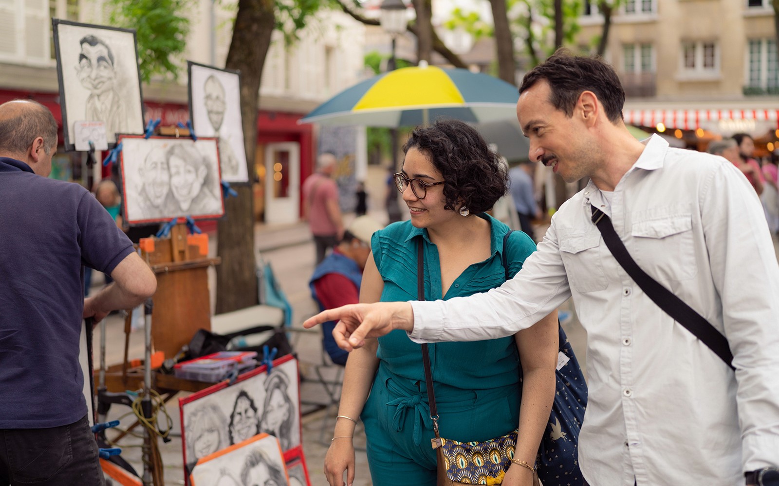 Mag-asawang nag-eexplore sa mga karikatura ng street artist sa Montmartre, Paris habang nasa guided walking tour.