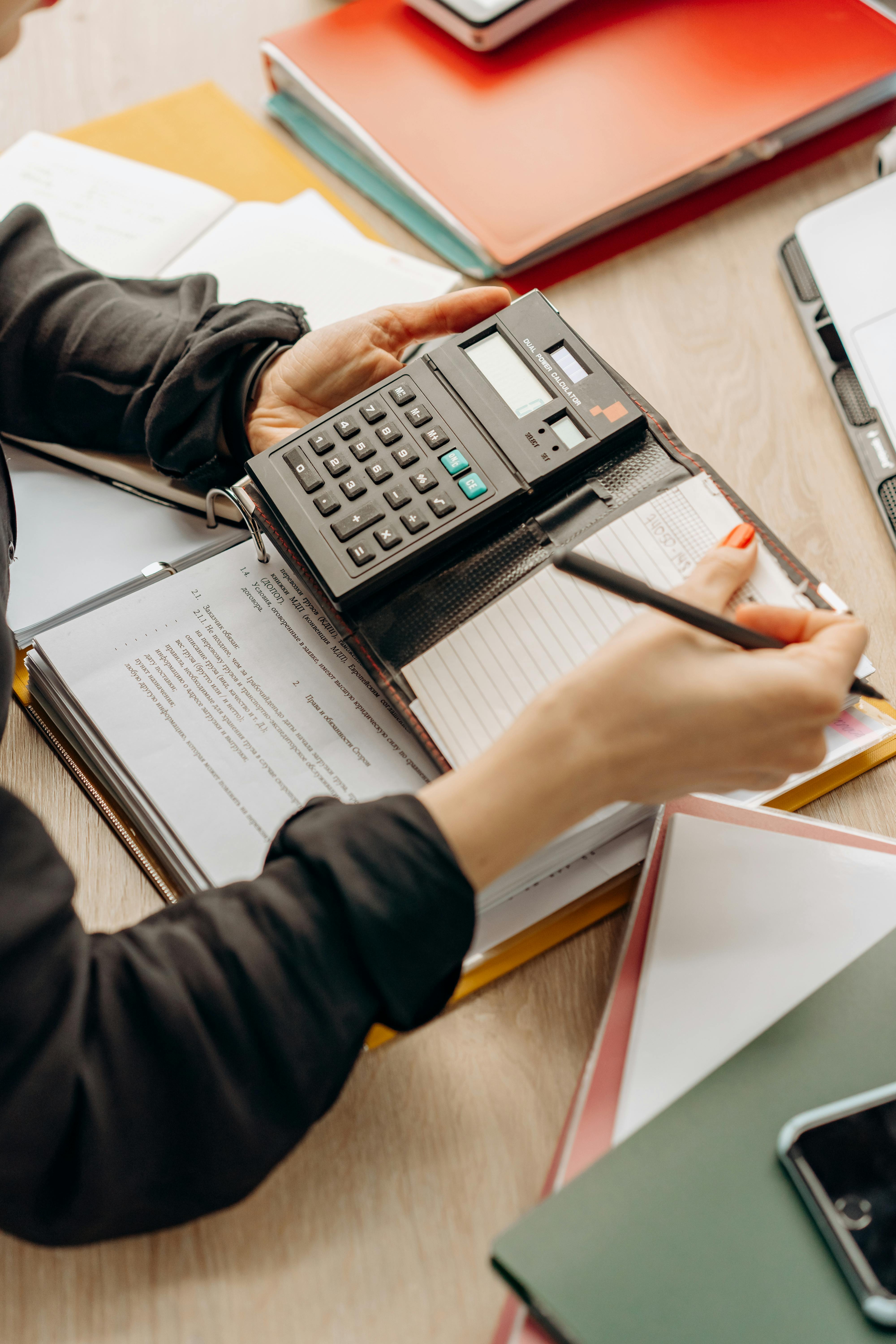 Une personne fait des papiers en utilisant la calculatrice