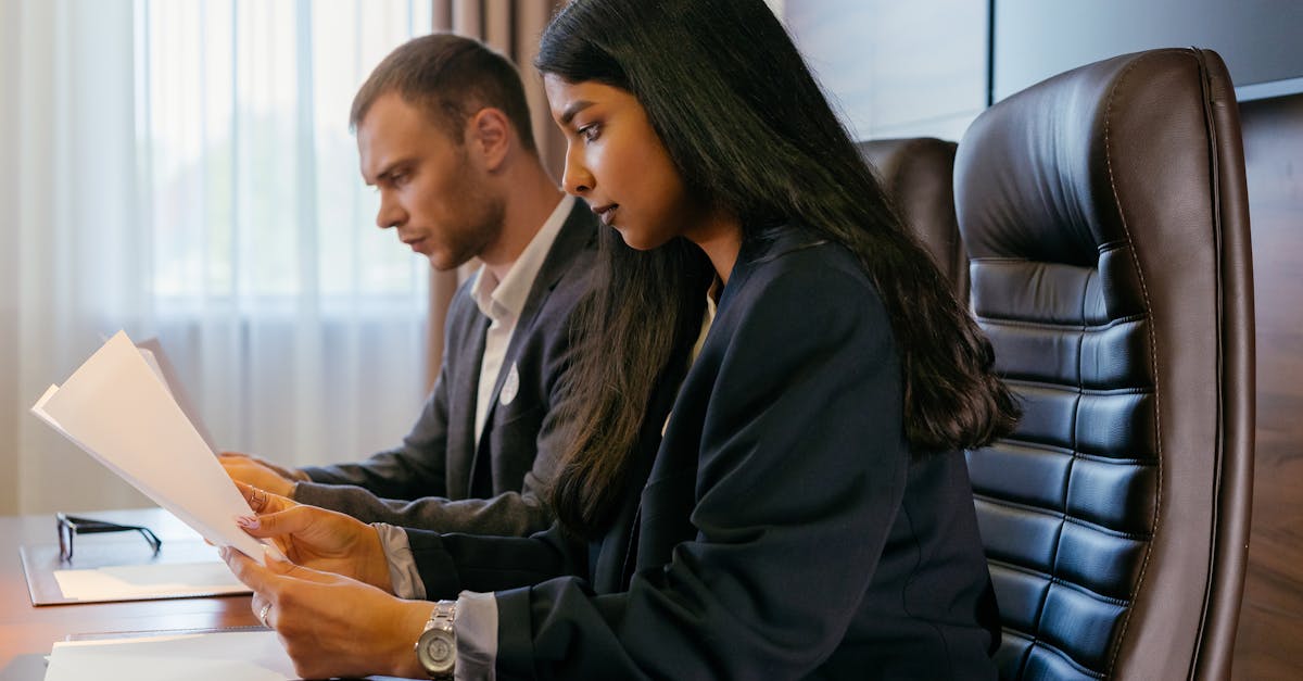 Two professionals reviewing documents in an office setting, showcasing teamwork and diversity.