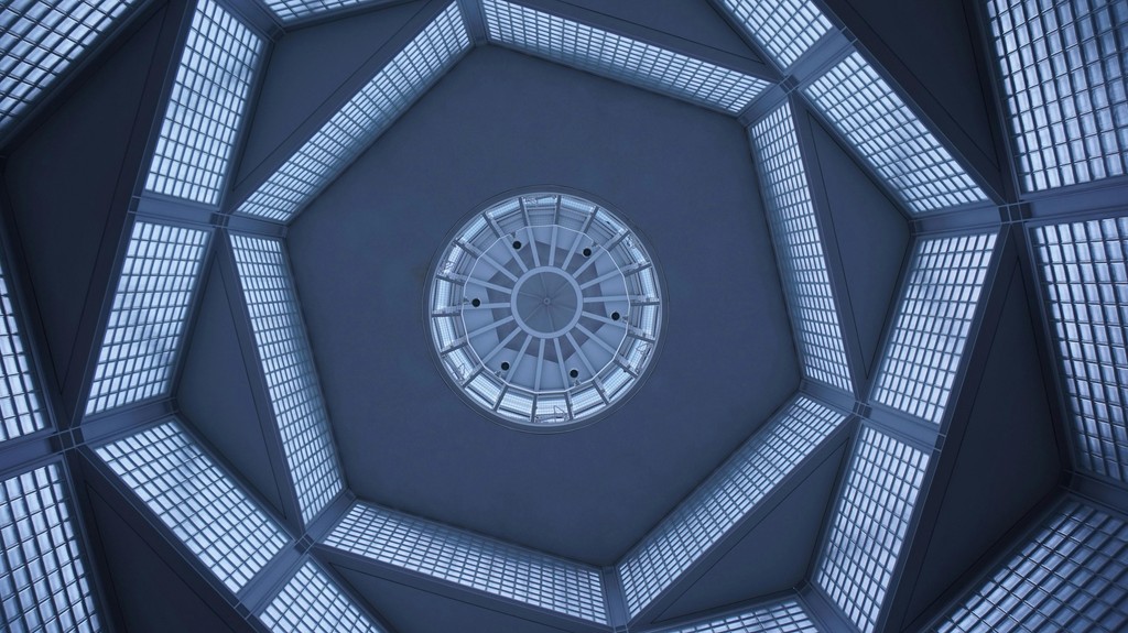 An Image of a geometric, dome-like ceiling with a central circular design and surrounding grid-like panels, suggesting modern architectural or industrial design elements.