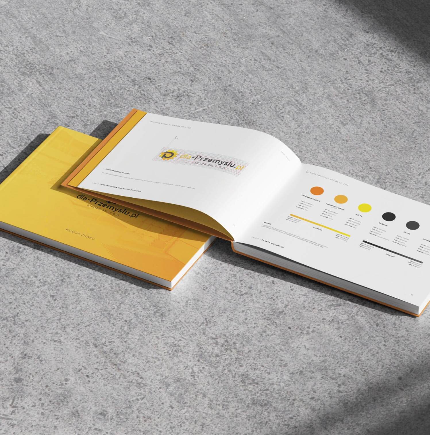 Otwarta i zamknięta drukowana księga znaku dla marki przemysłowej leżąca na betonowym podłożu.